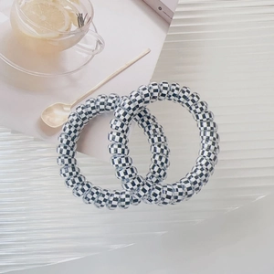 Close-up of two minimalist black and white checkerboard spiral phone cord hair ties