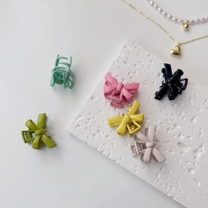 Set of colorful matte bow hair clips in various pastel shades displayed on a stone board