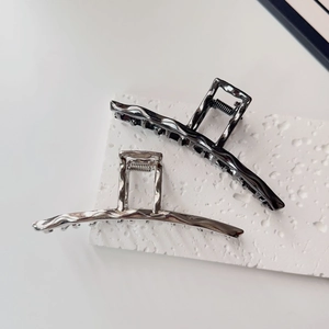 Detailed view of liquid metal style hair claws with wavy texture in silver and gunmetal