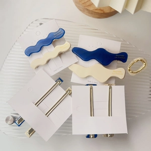 Makroaufnahme von wellenförmigen Haarspangen aus Acetat in Blau und Creme mit Golddruck