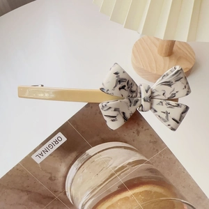 Detail of handmade cream acetate bow hair clip with marble pattern on a wooden background