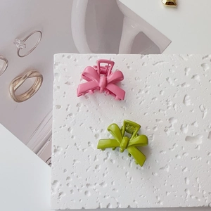 Close-up of pink and green bow hair clips on a textured stone surface display