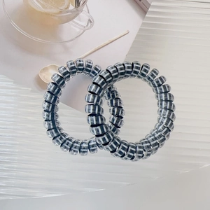 Detail of spiral telephone wire hair ties with black and white stripes on a desk