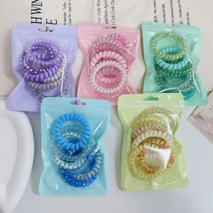 Set of pastel gradient spiral hair ties in colorful zipper bags on a clean white desk