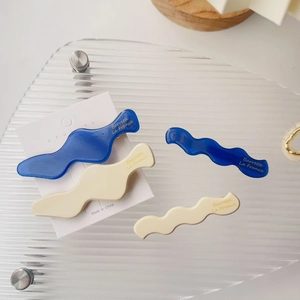 Detailansicht gewellter Acetat-Haarspangen in Marineblau und Creme mit Golddruck
