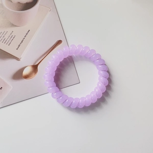 Close-up of a light purple spiral hair tie on a magazine showing the non-marking texture
