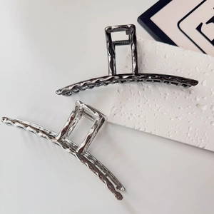 Detail of silver and gunmetal alloy hair claws with irregular molten lava metal textures