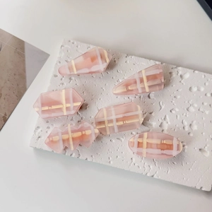 Vue à plat de six barrettes à cheveux roses à carreaux de diverses formes géométriques