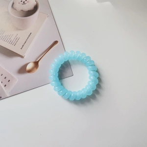 Detail shot of light blue spiral hair tie on white desk with aesthetic background