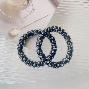 Detail of two black spiral hair ties with white heart print on a white background