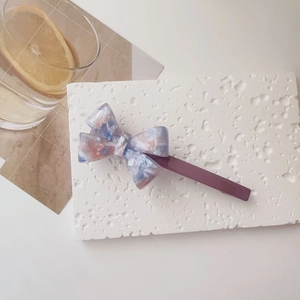 Detail of marble pattern acetate bow hair clip with spring barrette on stone base