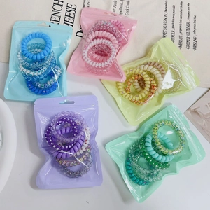 Macro shot of colorful pastel spiral hair ties sets in clear packaging on a white desk