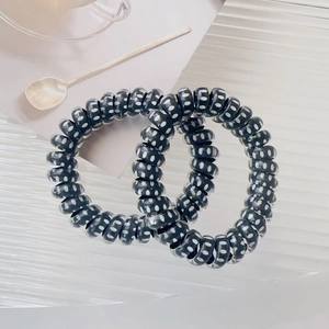 Detail view of two black spiral telephone cord hair ties with white polka dots