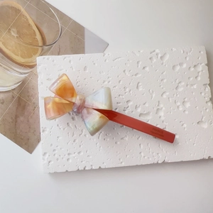 Detail of cream acetate bow hair clip showing France Handmade text on orange clip