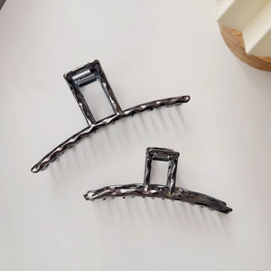 Detailed macro view of large gunmetal hair clips featuring artistic lava texture surface