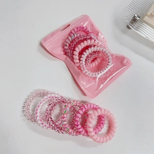 Pink gradient spiral hair ties set in a translucent zipper pouch on glass tray
