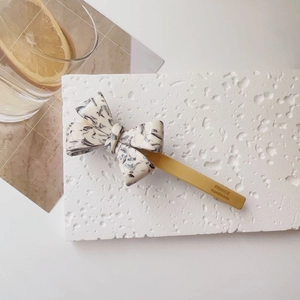 Detail of acetate bow hair clip showing the marble texture and France Handmade engraving