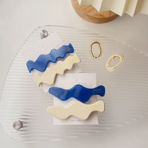 Detailansicht gewellter Acetat-Haarspangen in Marineblau und Creme auf Markenkarte