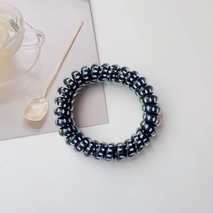 Detailed view of black spiral hair tie with white polka dots on soft background