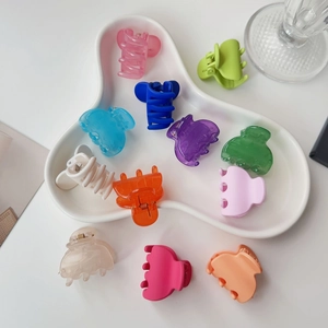 Close-up of 11 colorful matte and glossy mini hair claws on a ceramic plate
