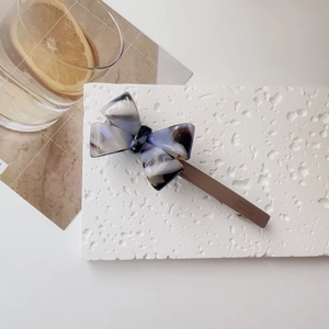 Close-up of marble texture acetate bow hair clip with vintage coffee brown base