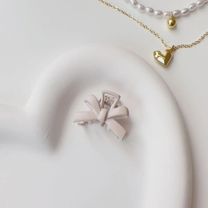 Detailed close-up of cream matte bow hair clip on a decorative jewelry tray