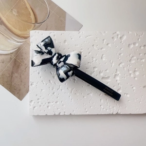 Detail of a marble-patterned acetate bow hair clip with gold France Handmade logo