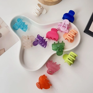 Close-up of matte candy-colored plastic hair claws set in a white ceramic tray