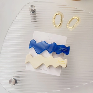 Detailansicht welliger Acetat-Haarspangen in Marineblau und Creme auf Displaykarte
