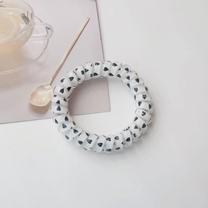 Detail shot of spiral hair tie featuring black heart patterns on a transparent base