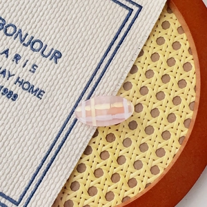 Vue détaillée d'une pince à cheveux à carreaux rose avec texture de résine douce