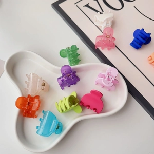 Close-up of candy-colored matte and transparent mini hair claws on a stylish white plate