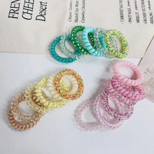 Close-up of colorful gradient spiral hair ties with glitter stars on a beige canvas background