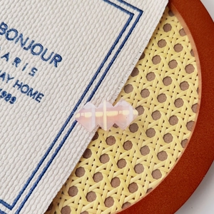 Vue détaillée d'une pince à cheveux géométrique en résine rose translucide sur un plateau
