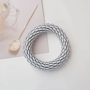 Detailed view of white and black striped spiral hair tie on a minimalist background