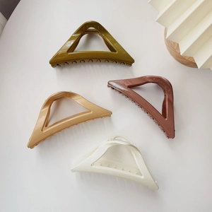 Détail de quatre pinces à cheveux triangulaires en couleurs vert olive, chameau, mocha et ivoire