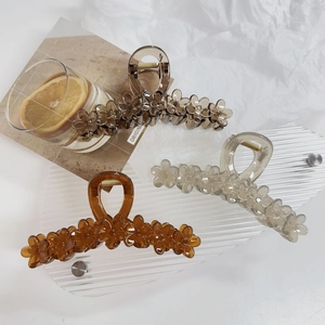 Detailed close-up of large flower shark clips in amber, gray, and translucent cream resin