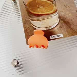 Close-up of matte orange small hair claw clip on wave pattern acrylic tray