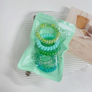 Close-up of assorted candy color gradient spiral hair ties in mint green zip packaging