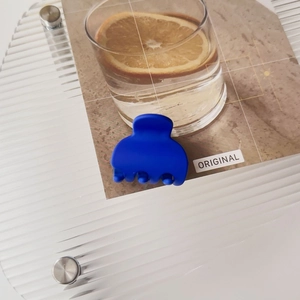 Detail view of small matte dark blue hair claw clip on a textured acrylic tray
