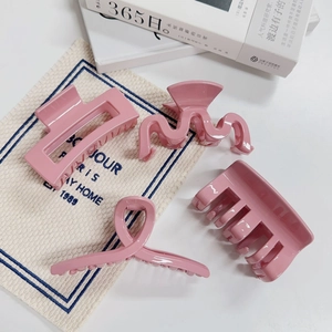 Lot de quatre pinces à cheveux roses avec finition brillante sur un fond minimaliste