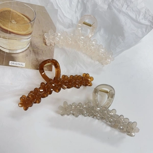 Detailed view of three resin flower hair claws in cream, amber, and smoky gray colors