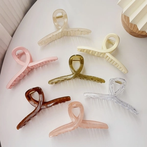 Oversized cross-loop hair claw clips set in 7 assorted colors on a white surface