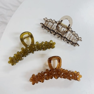 Three jelly-colored large flower claw clips in gray, olive green, and amber brown finish