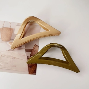 Détail de pinces à cheveux triangulaires beige et vert olive avec finition brillante sur blanc