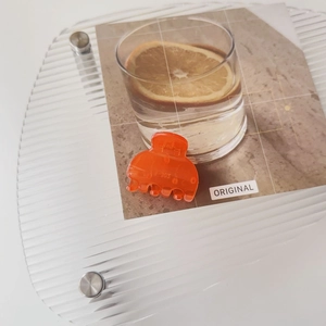 Detail view of orange frosted hair claw clip with V-305 engraving on acrylic surface
