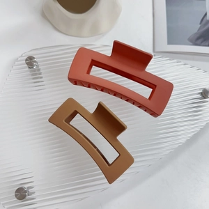 Dettaglio di grandi mollettoni per capelli opachi color rosso mattone e marrone caffè