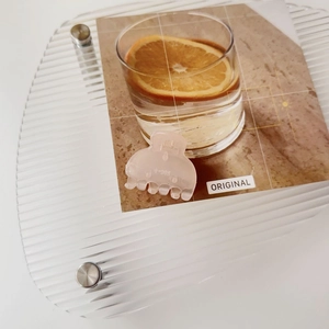 Detail of light pink resin hair claw Y-305 on a stylish textured display tray