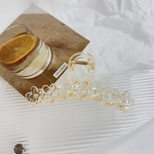 Detail view of transparent jelly flower hair claw with gold spring and resin petals
