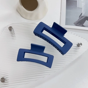 Dettaglio di due grandi mollette quadrate blu scuro opaco con estetica moderna raffinata